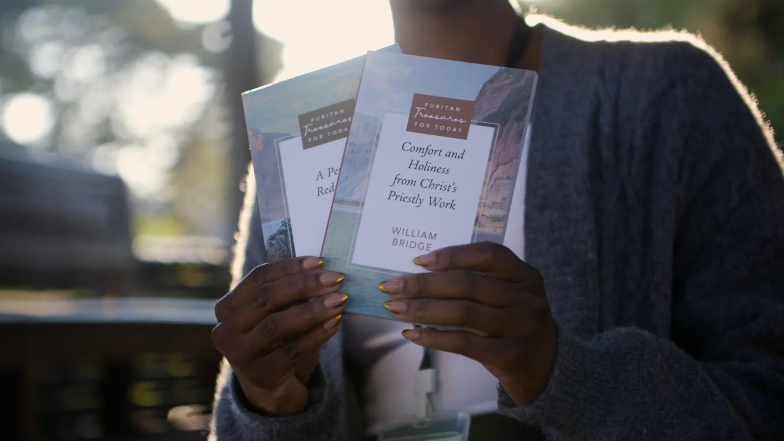 Hands hold up two Puritan Treasures for Today books, A Perfect Redeemer and Comfort and Holiness from Christ's Priestly Work.